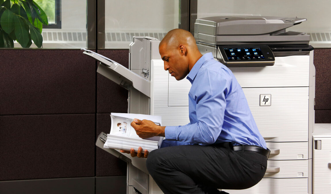 Man reading documents by an HP copier